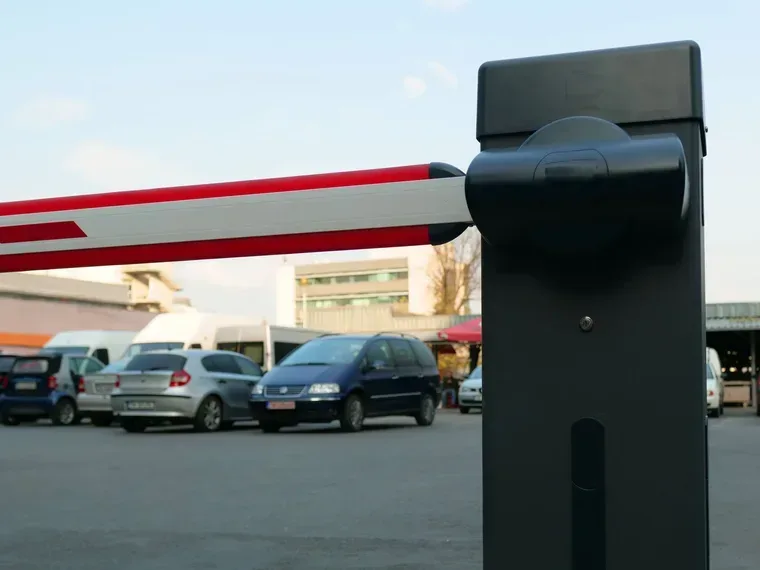 Otopark girişine kurulmuş kollu otomatik bariyer, kırmızı beyaz kollu ve motor kabinli